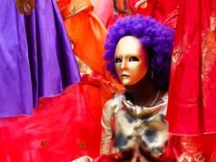 Disfraces identidad y tradición en eventos contemporáneos Persona eligiendo disfraz en tienda de Alcalá de Guadaíra con trajes coloridos y accesorios festivos.