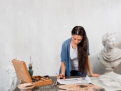 Criterios fundamentales al solicitar la valoración de obras de arte antiguas Especialista examinando un cuadro antiguo con lupa en un entorno de museo o galería.