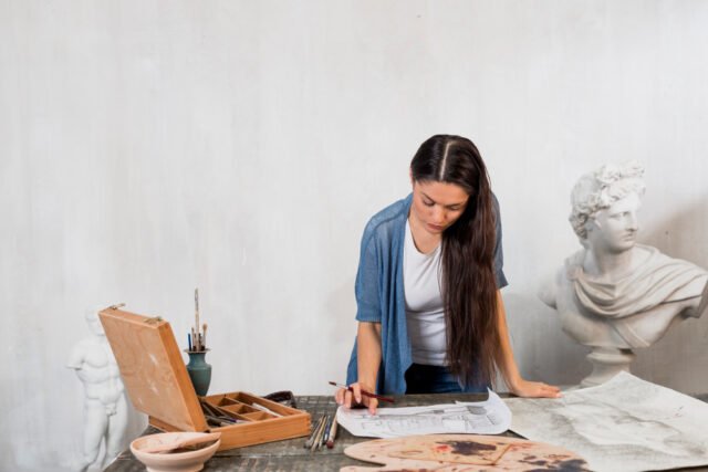 Especialista examinando un cuadro antiguo con lupa en un entorno de museo o galería.