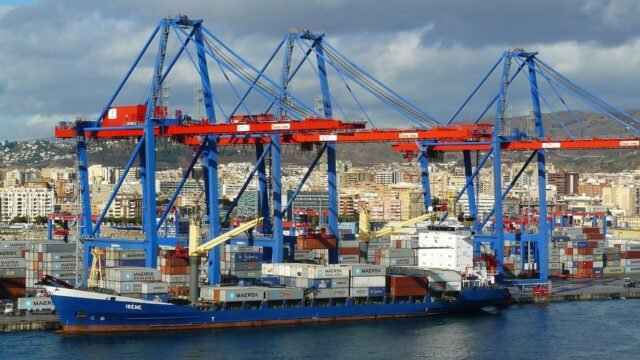 Puerto de Canarias con ferris sostenibles y contenedores inteligentes en un modelo de logística verde.
