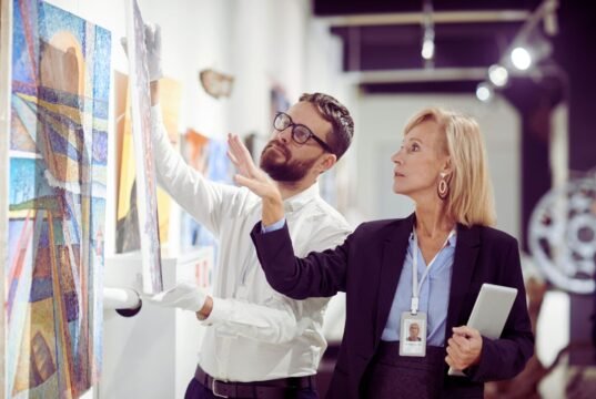 Profesionales clave para asegurar y valorar colecciones de arte con precisión Especialista analizando una obra de arte para su peritaje y valoración profesional.