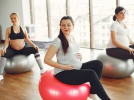Mujer embarazada realizando ejercicios de fisioterapia guiados por una profesional para aliviar molestias y preparar el cuerpo para el parto.